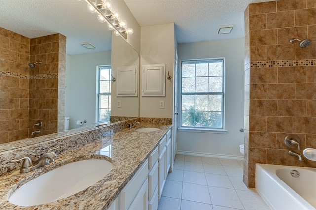 full bathroom with tile patterned flooring, vanity, a textured ceiling, toilet, and tiled shower / bath