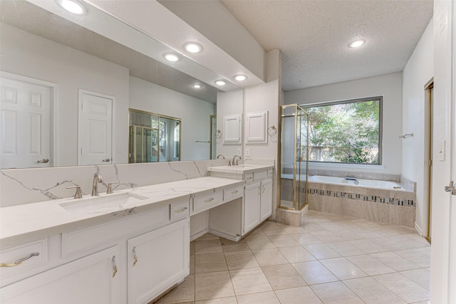 bathroom with independent shower and bath, vanity, tile patterned flooring, and a textured ceiling