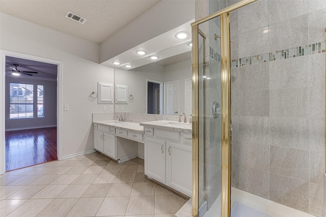 bathroom with walk in shower, tile patterned floors, a textured ceiling, vanity, and ceiling fan