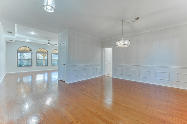 spare room featuring ceiling fan with notable chandelier, ornamental molding, and light hardwood / wood-style floors