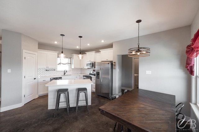 kitchen with appliances with stainless steel finishes, pendant lighting, sink, white cabinets, and a center island