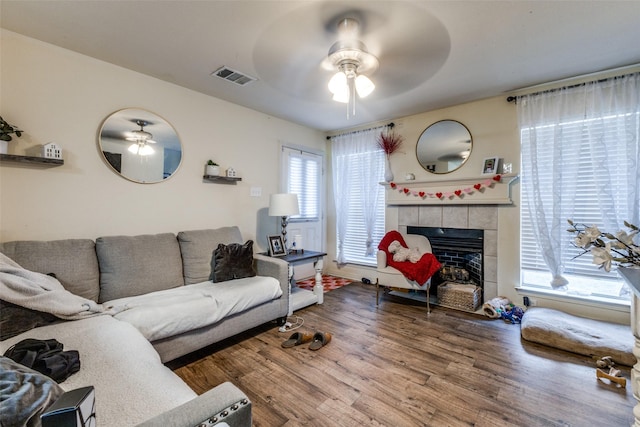 living room featuring a tiled fireplace, hardwood / wood-style flooring, and ceiling fan