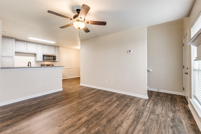 unfurnished living room with dark hardwood / wood-style flooring, sink, and ceiling fan