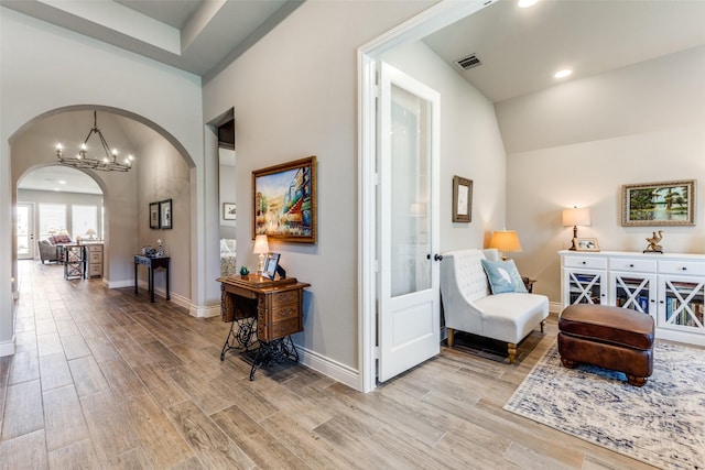 sitting room with an inviting chandelier, vaulted ceiling, and light hardwood / wood-style flooring