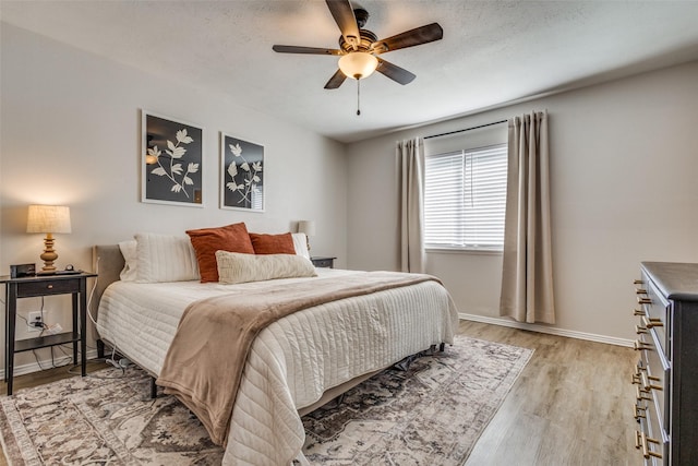 bedroom featuring ceiling fan, light hardwood / wood-style flooring, and a textured ceiling