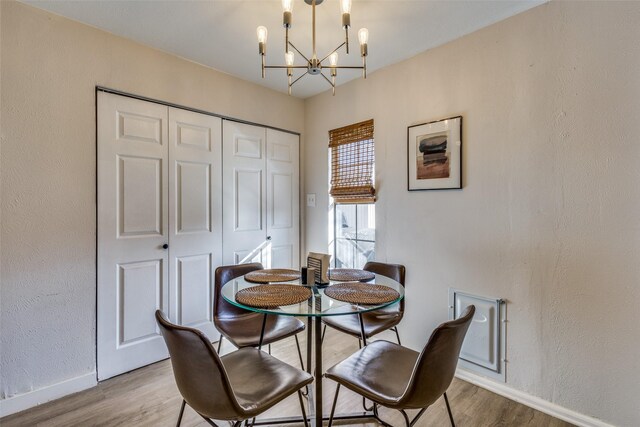 dining area with hardwood / wood-style floors and an inviting chandelier