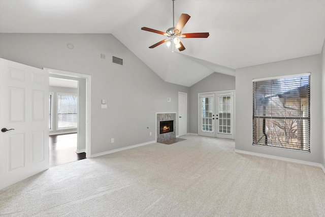 unfurnished living room with a tile fireplace, ceiling fan, high vaulted ceiling, light carpet, and french doors