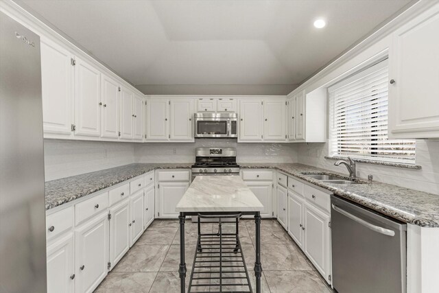 kitchen with ceiling fan, backsplash, a sink, appliances with stainless steel finishes, and white cabinetry
