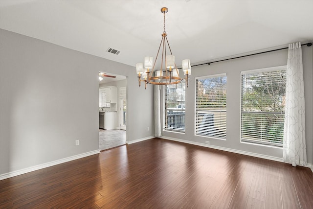 unfurnished dining area with dark hardwood / wood-style flooring and ceiling fan with notable chandelier