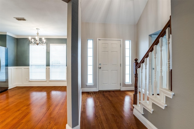 foyer featuring an inviting chandelier, ornamental molding, and dark hardwood / wood-style floors