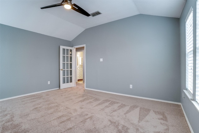 carpeted spare room featuring vaulted ceiling and ceiling fan