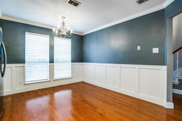 empty room featuring crown molding, hardwood / wood-style floors, and a notable chandelier