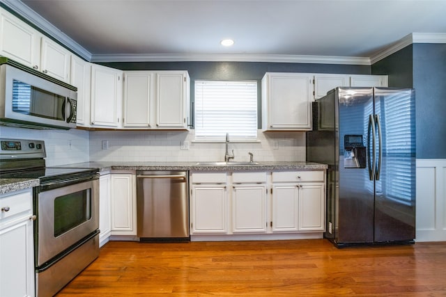 kitchen with stainless steel appliances, ornamental molding, sink, and white cabinets