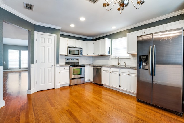 kitchen featuring sink, white cabinetry, light hardwood / wood-style flooring, stainless steel appliances, and decorative backsplash