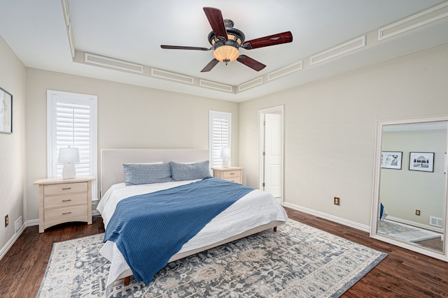 bedroom featuring ceiling fan, a tray ceiling, and dark hardwood / wood-style floors