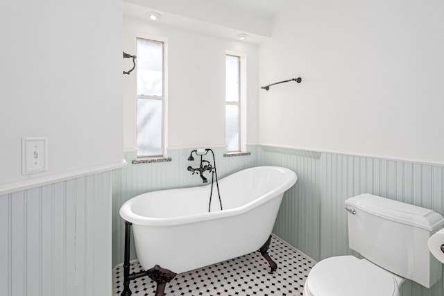 bathroom featuring tile patterned floors, toilet, and a washtub