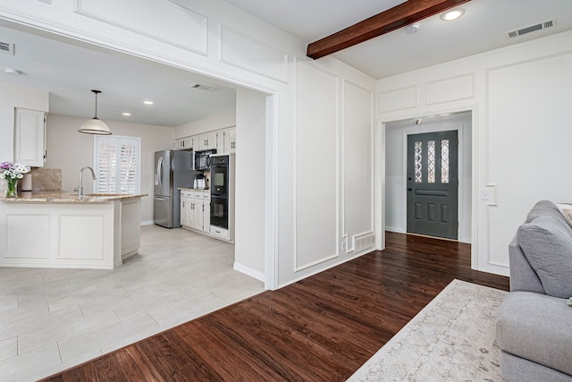 entrance foyer featuring light hardwood / wood-style floors and beamed ceiling