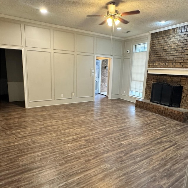 unfurnished living room featuring dark wood-type flooring, ornamental molding, a fireplace, and a textured ceiling