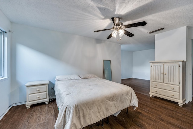 bedroom featuring dark wood-type flooring, ceiling fan, and a textured ceiling