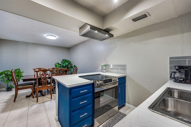 kitchen featuring electric stove, sink, light tile patterned floors, blue cabinetry, and wall chimney exhaust hood