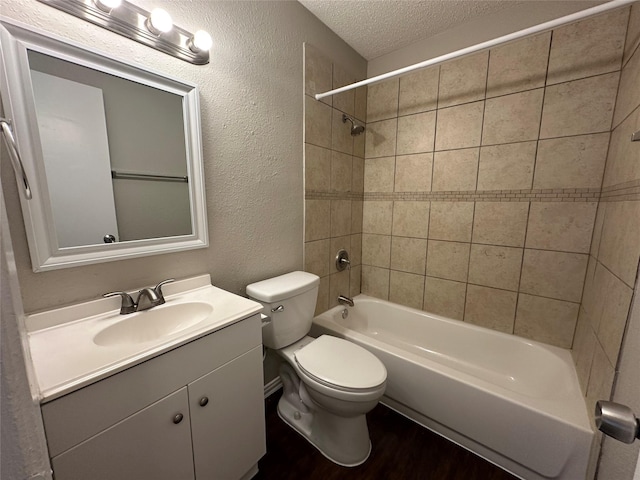 full bathroom with toilet, tiled shower / bath, wood-type flooring, a textured ceiling, and vanity