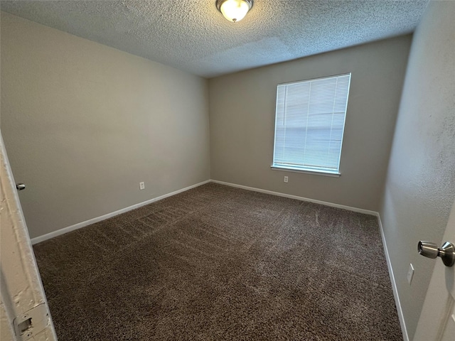 spare room with a textured ceiling and dark colored carpet