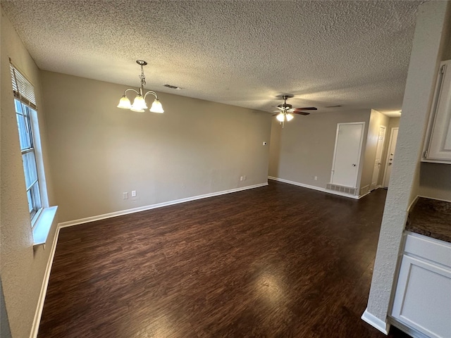 unfurnished living room with dark wood-type flooring, ceiling fan with notable chandelier, and a textured ceiling