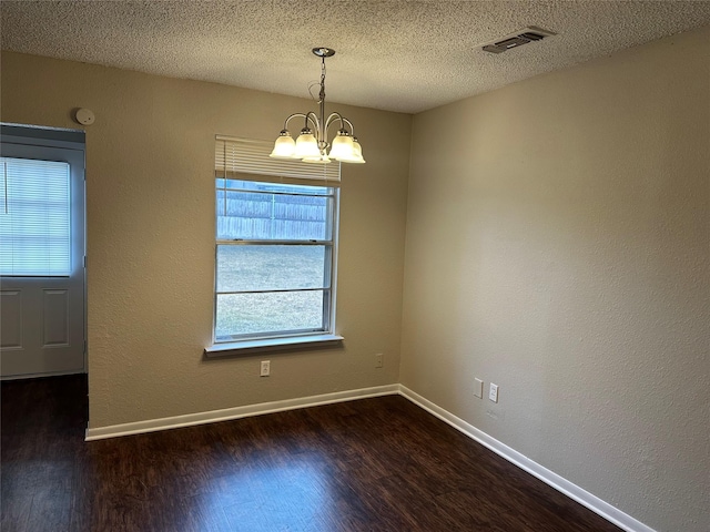 unfurnished dining area with dark wood-type flooring, a notable chandelier, and a textured ceiling