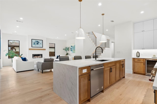 kitchen featuring pendant lighting, sink, white cabinetry, a kitchen island with sink, and beverage cooler