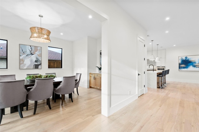 dining space featuring sink, an inviting chandelier, and light wood-type flooring