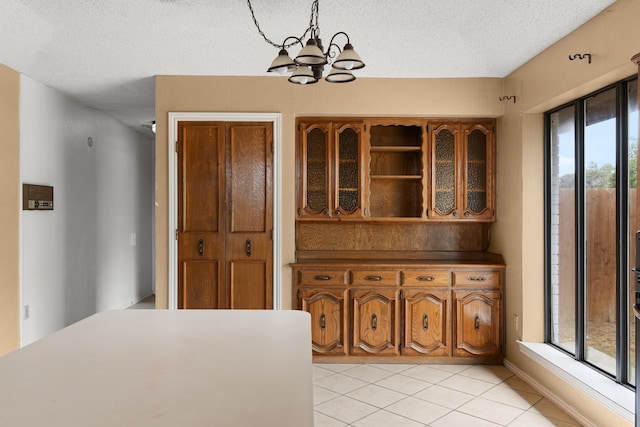 unfurnished dining area with a chandelier, a textured ceiling, and light tile patterned floors