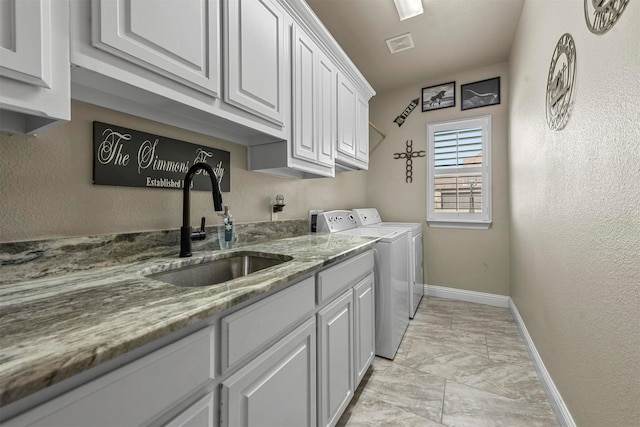 clothes washing area featuring sink, cabinets, and independent washer and dryer