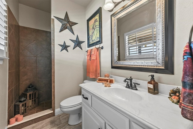 bathroom featuring tiled shower, vanity, and toilet