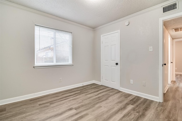 empty room featuring crown molding, light hardwood / wood-style flooring, and a textured ceiling