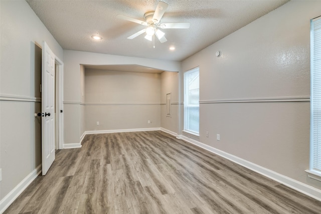 empty room featuring ceiling fan, wood-type flooring, and a textured ceiling