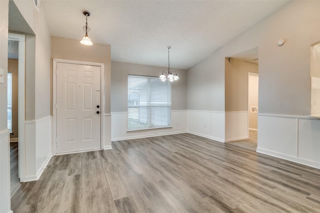 foyer with hardwood / wood-style flooring, lofted ceiling, a chandelier, and a textured ceiling