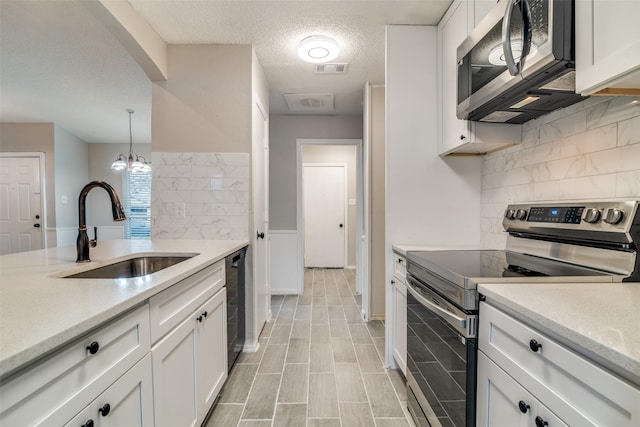 kitchen featuring sink, appliances with stainless steel finishes, hanging light fixtures, tasteful backsplash, and white cabinets