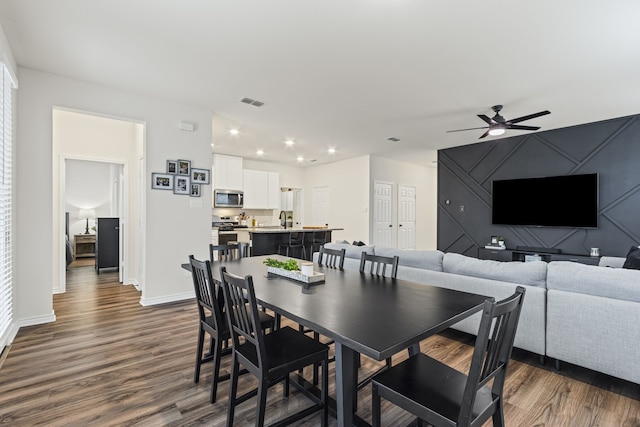 dining area featuring dark wood-type flooring, ceiling fan, and sink