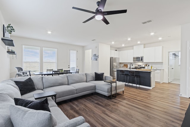 living room with wood-type flooring, sink, and ceiling fan