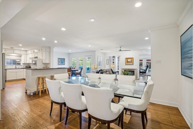 dining space with sink, light hardwood / wood-style flooring, and ceiling fan