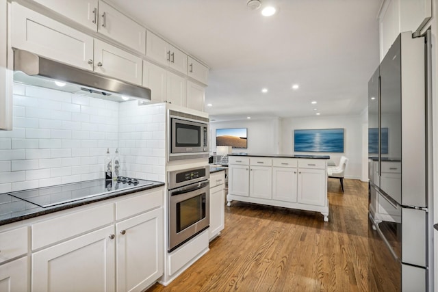 kitchen with tasteful backsplash, stainless steel appliances, light hardwood / wood-style floors, and white cabinets