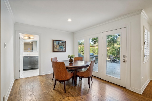 dining room with sink, wood-type flooring, and ornamental molding