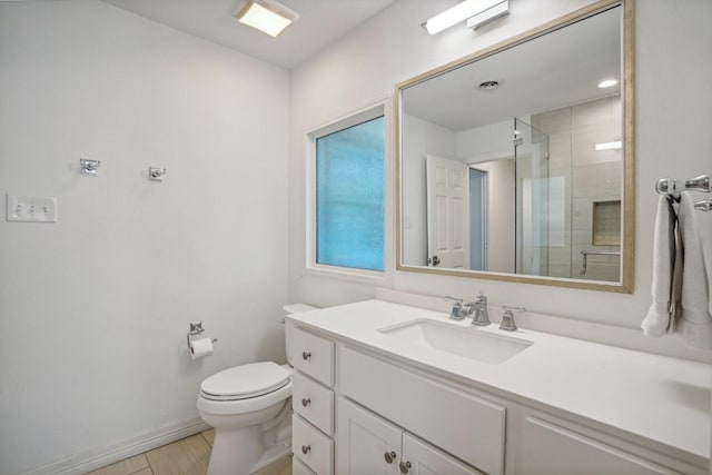 bathroom with a shower with door, vanity, and toilet