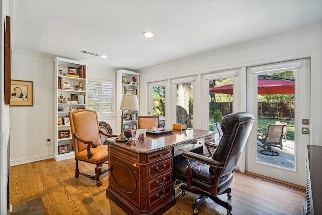 home office with ornamental molding and light hardwood / wood-style floors