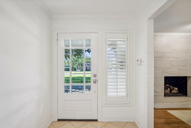 entryway with crown molding, light tile patterned floors, and a fireplace