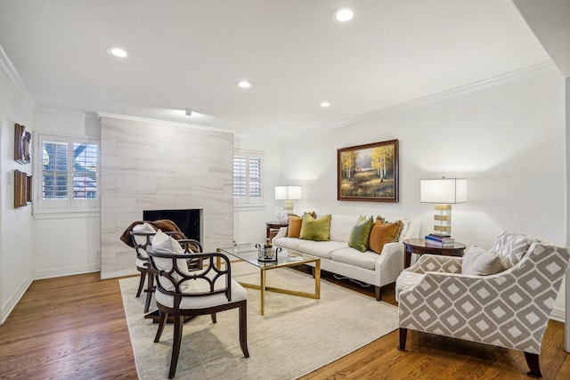 living room with wood-type flooring, ornamental molding, and a fireplace