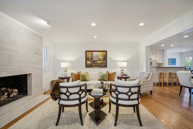 living room featuring ornamental molding, a premium fireplace, and light hardwood / wood-style floors