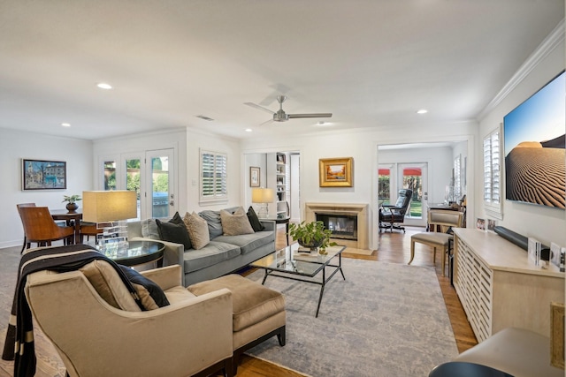 living room featuring ornamental molding, light wood-type flooring, and french doors