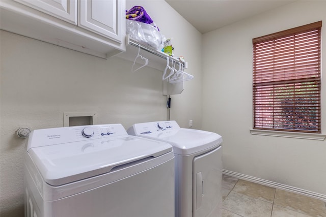 laundry room with washer and dryer, cabinets, and light tile patterned flooring