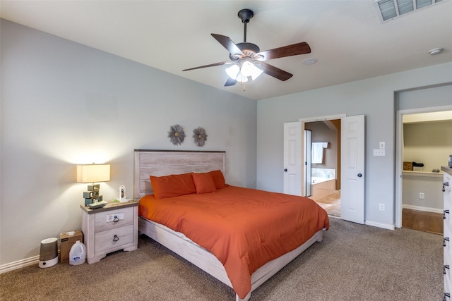 bedroom with ceiling fan, light colored carpet, and ensuite bath